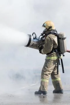 One firefighter extinguish fire from fire hose, using firefighting water-foam Stock Photos