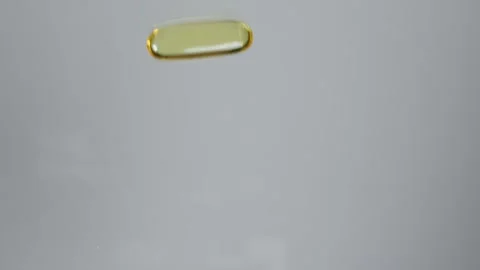 One fish oil capsule is rolled over a transparent surface Stock Footage 267420904
