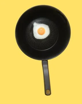 One fried egg in hot pan on yellow background, top view Stock Photos
