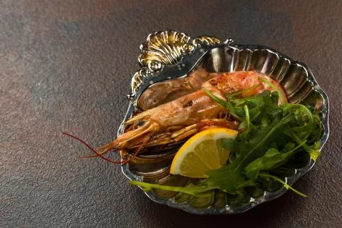 One Fried Tiger Prawn or langostino with greens and Lemon on ancient plate Stock Photos