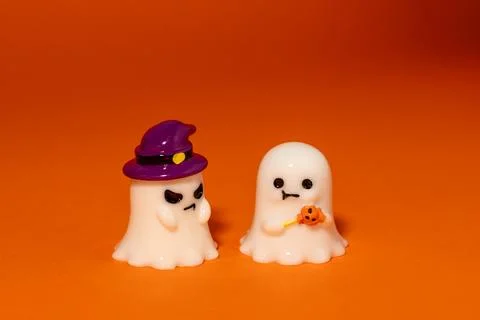 One ghost wears a purple witch hat and looks angry on second ghost, while h.. Fotos de archivo