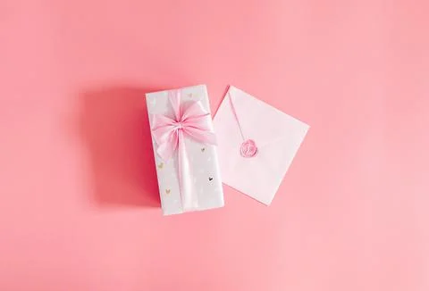 One gift box with an envelope on a pink background. Stock Photos