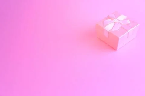 One gift or present box with a white ribbon bow on a pink trend background. V Stock Photos