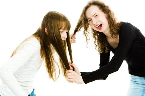 One girl abusing other by pulling her hair. Afraid and scared girl screaming Stock Photos