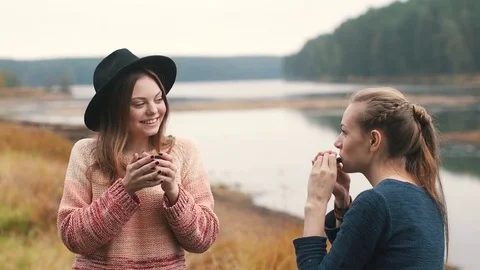 One girl plays harmonica and another girl listens music and drinks hot tea Stock Footage 69764823