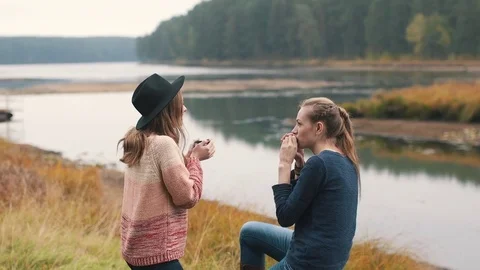One girl plays harmonica and another girl listens music and drinks hot tea Stock Footage 69765345