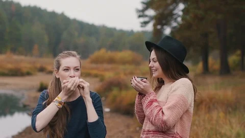 One girl plays harmonica and another girl listens music and drinks hot tea Stock Footage 69765466