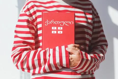 One girl, whose face is not visible in a striped red long sleeve, holds a r.. Stock Photos