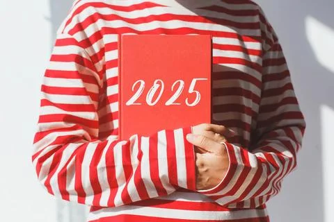 One girl, whose face is not visible in a striped red long sleeve, holds a red Stock Photos