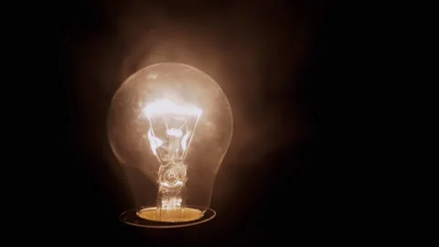 One Glowing Incandescent Light Bulb in Thick Smoke on Black Background 動画素材 258808081