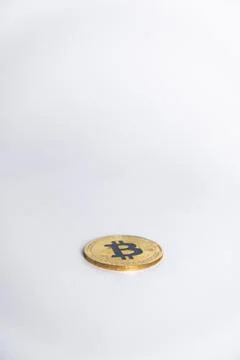 One gold Bitcoin faced down centered on table in a light grey background Stock Photos