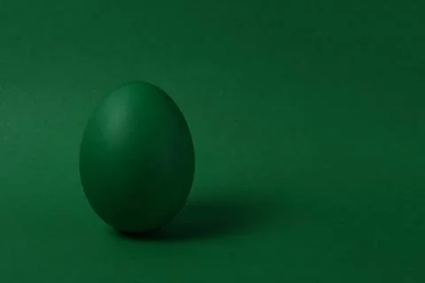 One green painted Easter egg stand on a green background. Stock Photos