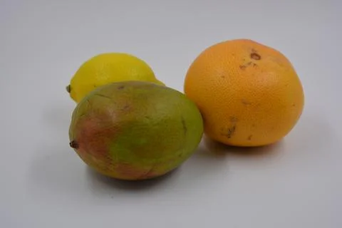 One green-red mango, one yellow lemon, one red-orange grapefruit. Stock Photos
