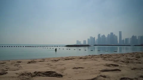 One guy leaving the sea alone in front of Doga Skyline in a beautiful morning Stock Footage 150959983