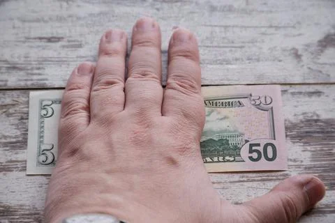 One hand covers two bills of five and fifty dollars, increase in profits, hid Stock Photos