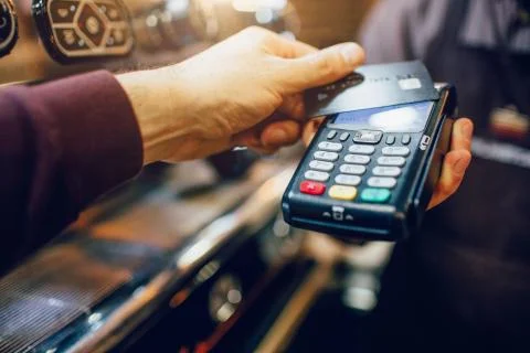 One hand hold machine for cards white another hold dark card for paying money Stock-Fotos