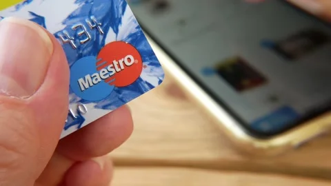 One hand holding MasterCard from Mestro other hand using mobile phone for sho Stock Footage 211807860