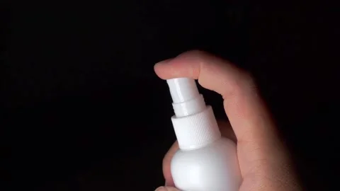 One hand is holding a white spray bottle and pressing the bottle cap to spray a  Stock Footage 155481333