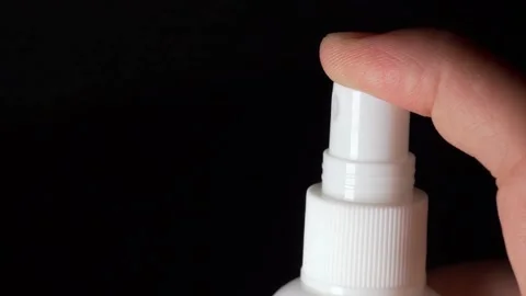 One hand is holding a white spray bottle and pressing the bottle cap to spray a  Stock Footage 155481334
