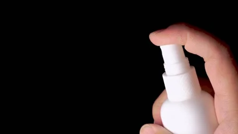 One hand is holding a white spray bottle and pressing the bottle cap to spray a  Stock Footage 155481335