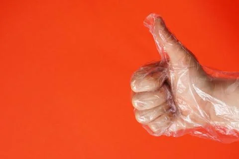 One hand in plastic or rubber protective disposable gloves on red background. Stock Photos