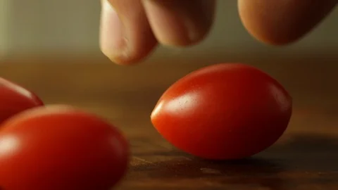 One Hand Taking In and Out Tomato in a Wooden Surface Stock Footage 86130563