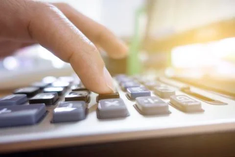 One hand is using calculator with blur bokeh at the background. Stock Photos