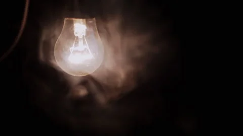 One Hanging, Glowing Light Bulb with a Wire in Thick Smoke on a Black Background Stock Footage 253581949