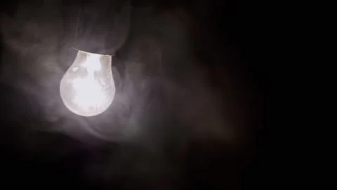 One Hanging, Glowing Light Bulb in Thick Smoke on a Black Background Stock Footage 253582049