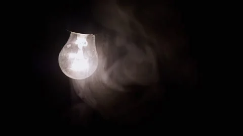 One Hanging, Glowing Light Bulb in Thick Smoke on a Black Background Stock Footage 253772180