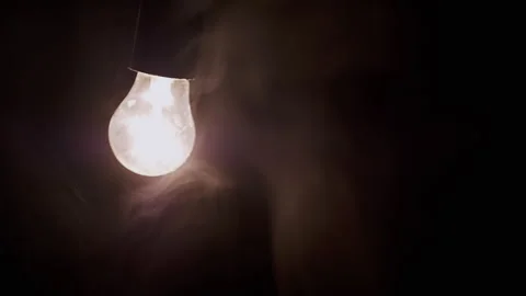 One Hanging, Glowing Light Bulb in Thick Smoke on a Black Background Stock Footage 253772194