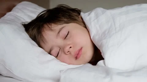 One happy boy sleeps in bed under blanket. The child at daytime relax. Stock Footage 234966496