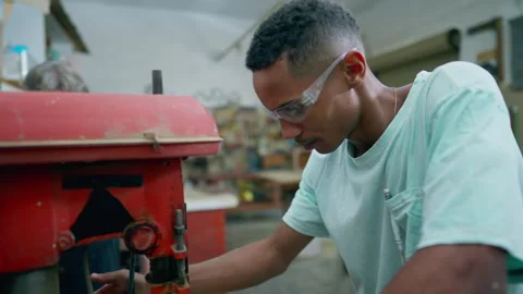 One happy young black carpentry apprentice using industrial machine, turns .. Video stock 255871710