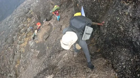 One hiker helps a second hiker up a large rock. First-person view Stock-Footage 169224957