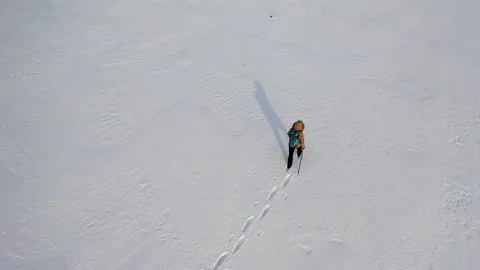 One human in winter clothes with backpack and ski poles walks through endless Stock Footage 211681129