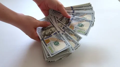 One hundred dollar bills inspected and counted by female hands on white Stock Footage 345180837