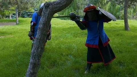 One knight shows another how to practice blows with a sword on a tree 스톡 동영상 122079961