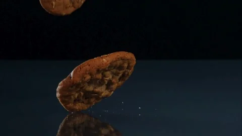 One large cookie falling and hitting a dark surface with small crumbs Stock Footage 326629688