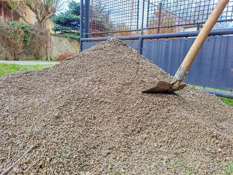 One large pile of gray rubble with a shovel and small stones in the street road Stock Photos