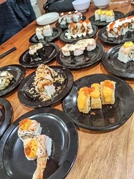 One large table contains many sushi plates in a Japanese restaurant Stock Photos