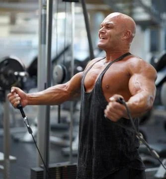 One last rep. A male bodybuilder using exercise equipment to train at the gym. Stock Photos