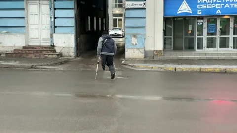 One-legged disabled person walking with crutches сrossing the road Stock Footage 139222059