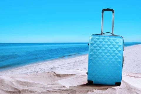 One light blue suitcase on sandy beach near sea. Space for text Stock-Fotos