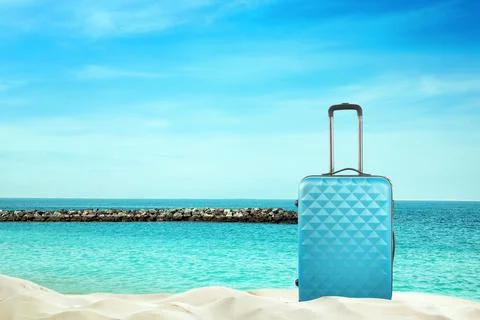 One light blue suitcase on sandy beach near sea. Space for text Stock-Fotos
