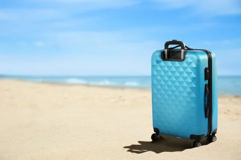 One light blue suitcase on sandy beach near sea. Space for text Stock-Fotos