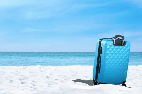 One light blue suitcase on sandy beach near sea. Space for text Stock-Fotos
