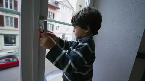 One little boy holding into window knob handle from second floor apartment,.. Photos