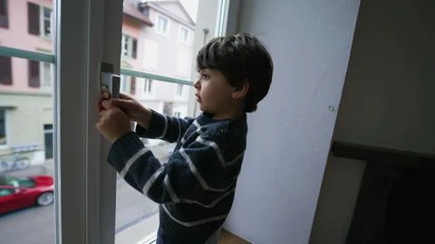 One little boy holding into window knob handle from second floor apartment,.. Photos