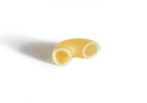 One macaroni isolated on a white background. Macro. Horn Stock Photos