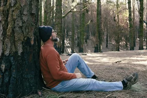 One man having relaxation time sitting on the ground in the middle of green.. Stock Photos